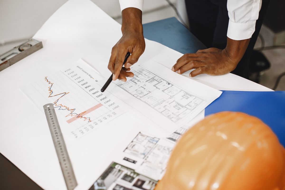 Illustrative architectural plans and financial documents on a desk, not the actual chambers